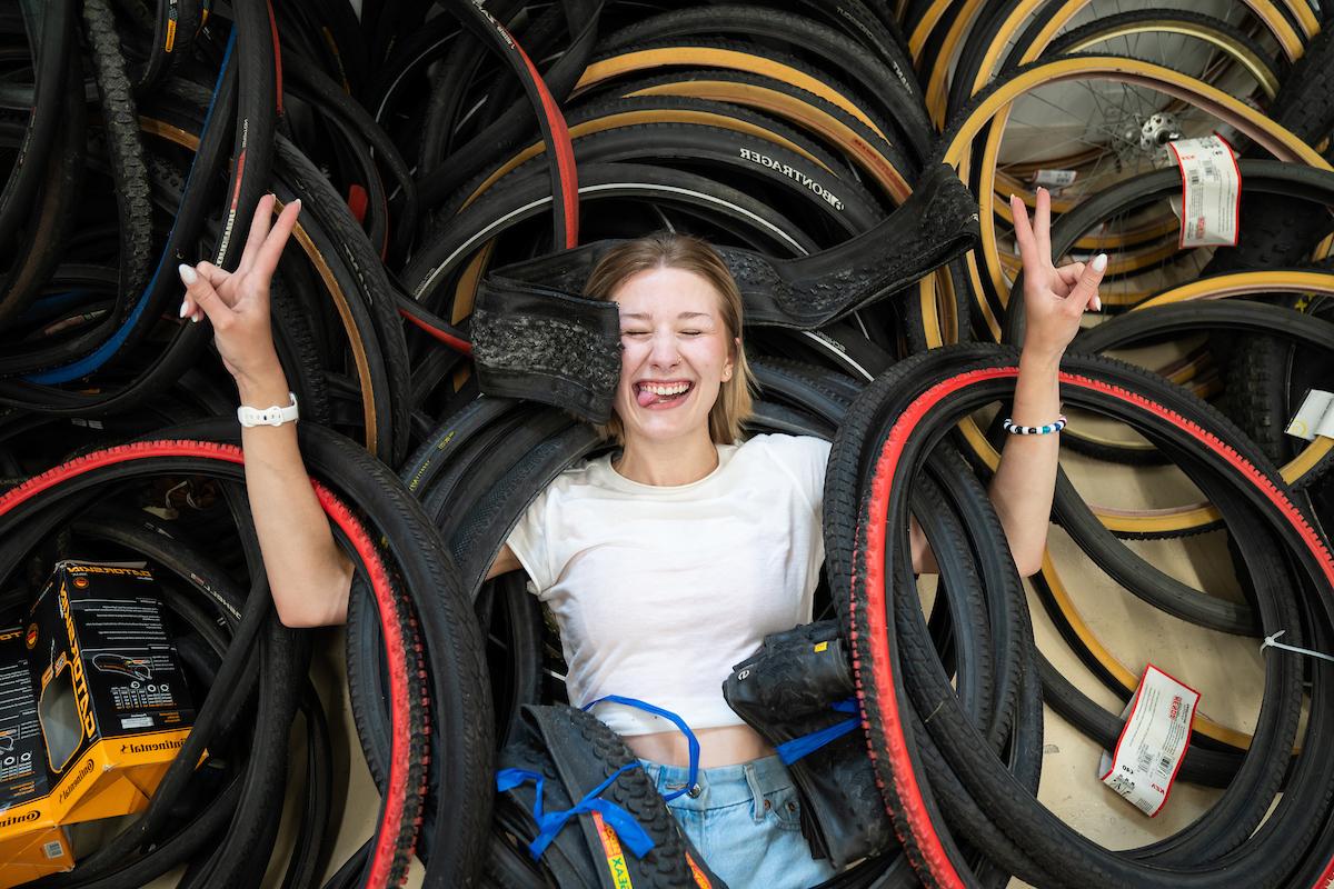 Arabella Cummings holding up peace signs in a pile of bicycle tires.